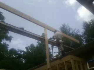 Carpenter setting a ridge beam over a new addition frame — Ice Dam Removal by Roofing Brothers in Grosse Pointe