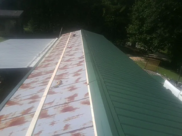 Old rusted panels beside newly installed green metal roofing — Wind Damage Roof Repair by Roofing Brothers in Grosse Pointe