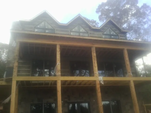 Dormers and porch framing on a large log home under construction — Roof Coating work by our crew in Grosse Pointe