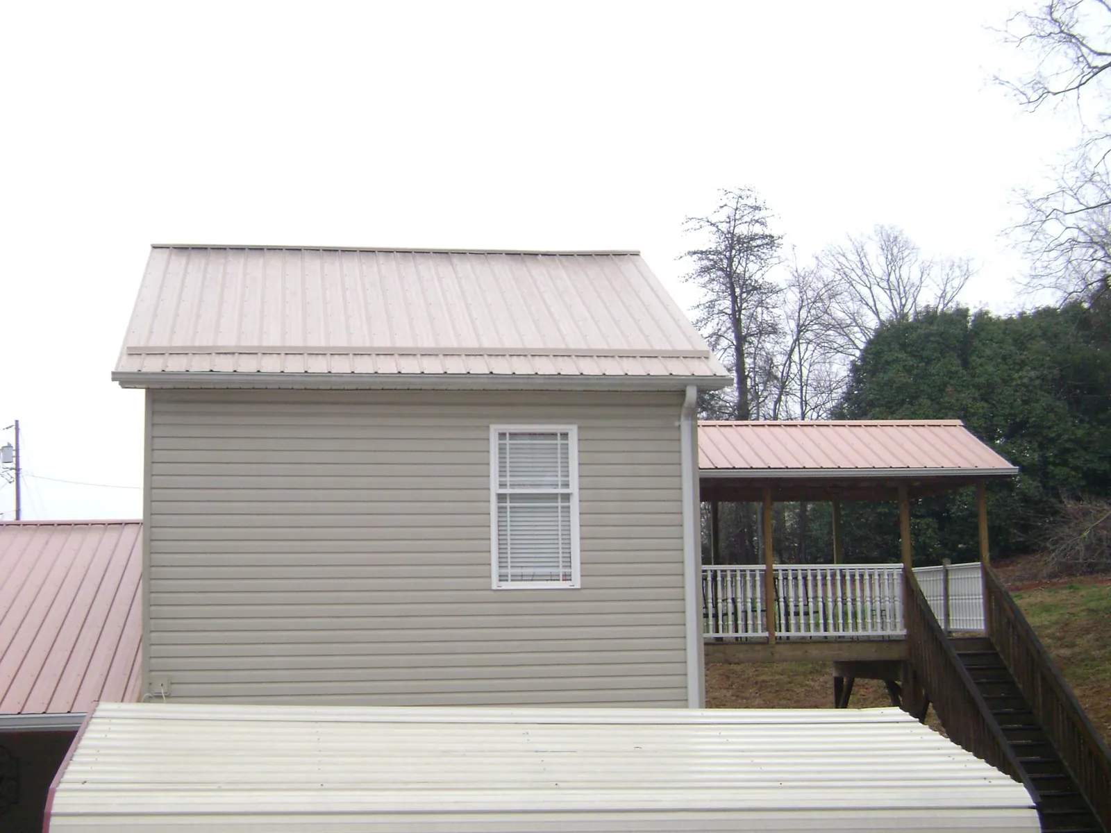 Tan metal roofs on a two story addition and attached porch, from a Roof Replacement job in Grosse Pointe